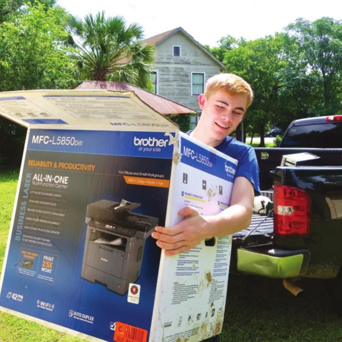 La Grange High School soon-to-be senior Sean Green carries equipment donated by Mike Koeth and CompuCleanser in Weimar.