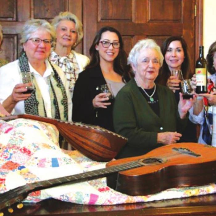 Festival Hill Gala Planning Committee doing a tasting from Majek Winery. A selection of auction items in the front. The quilt is donated from James Dick and belonged to his first piano teacher Leota Anderson. Pictured are (from left) Judy Hancock, Pat Johnson, Pat McMahen, Susannah Mikulin, Joanie Havlick, Sandy Millyer and Co-Chair Katrina Elvig.