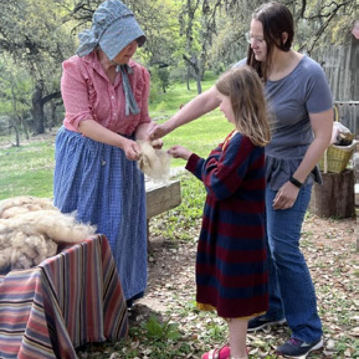 Living historian Bobbie Nash teaches families about the wool spinning process during a weekend activity. Stepping back in time, living history volunteers show audiences different life skills and practices from the late 19th century.