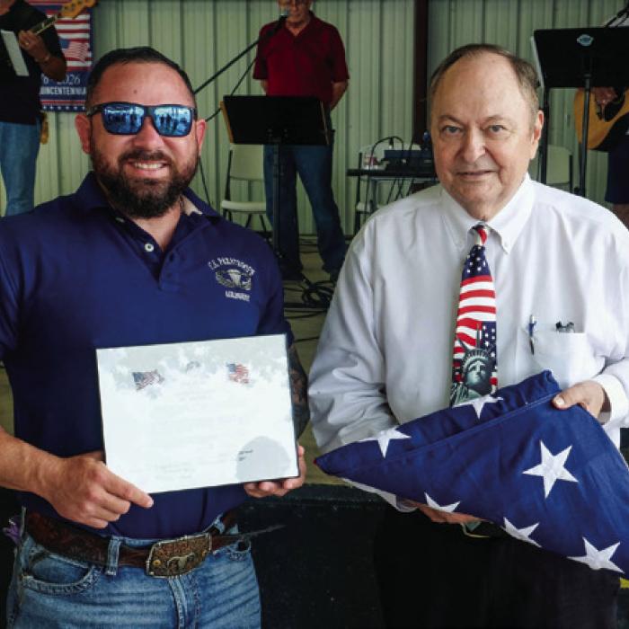 Left, a color guard comprised of veterans from across the County march in the flags. Right, local veteran Dustin Blackwell presented County Judge Dan Mueller with a flag he carried during a parachute jump over Normandy on the anniversary of D-Day. Photos by Andy Behlen