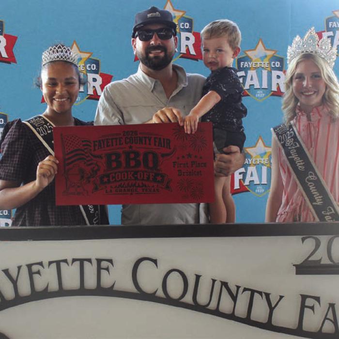 Silver Bullet Cookers (in addition to being Overall Grand Champions, see Page 1A today) won first place brisket and first place pork ribs at Saturday’s Fayette County Fair Bar-B-Q Cook Off. Left to right 2025 Queen second runner-up Keanna Henderson, head cook Brock Otto, holding Brant Otto and 2025 Fair Queen Hailey Janish.