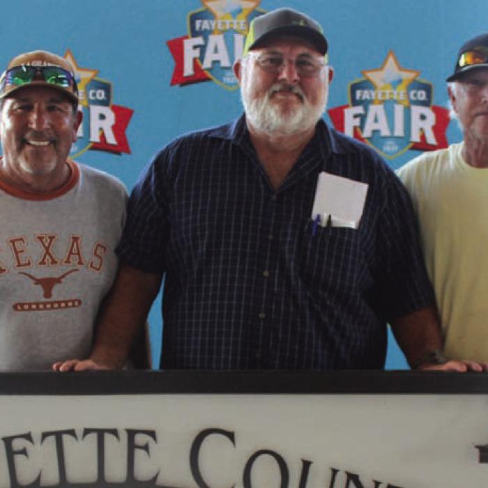 Fayette County Fair Bar-B-Q committee members Hector Cervantes, George Eilert and chairman Jimmy Rohde take a break from their hard work Saturday to pose for a photo.