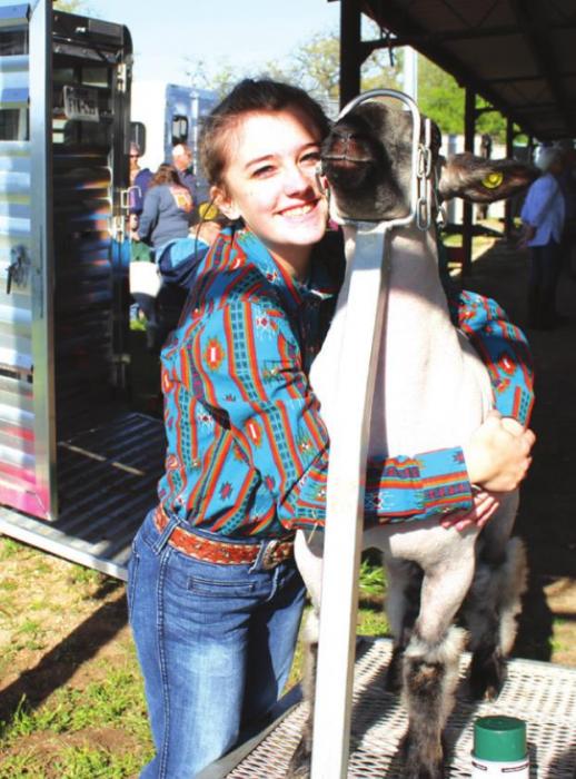 Shaylee McCoy gives her lamb a hug before her show Friday.