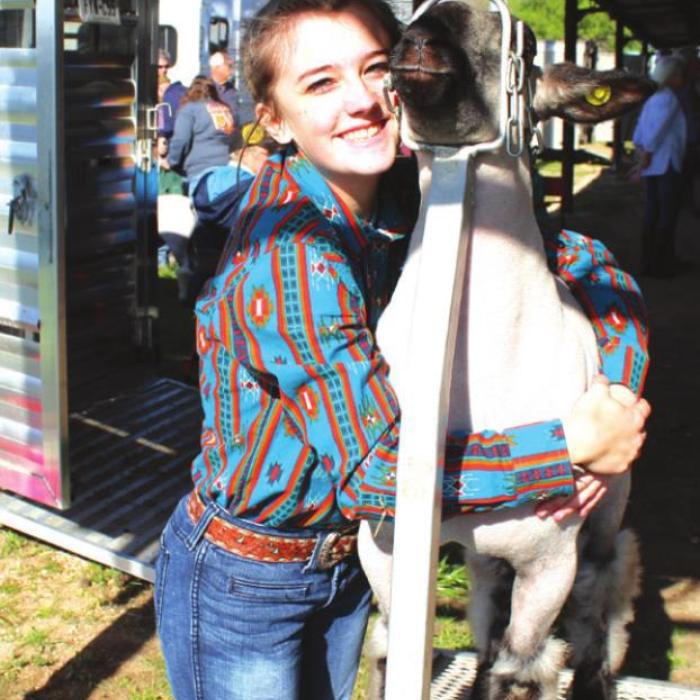 Shaylee McCoy gives her lamb a hug before her show Friday.
