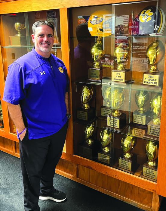 Matt Kates stands in front of a trophy case at the La Grange field house Wednesday filled with gold footballs representing his playoff wins and district titles at the school during his 13 years as head coach. He resigned this week. Photo by Jeff Wick