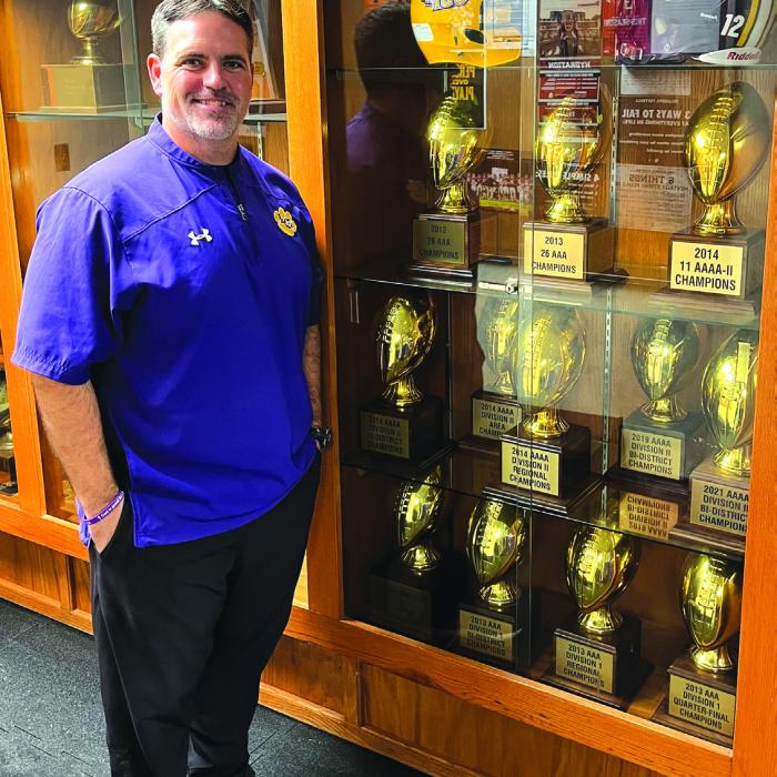 Matt Kates stands in front of a trophy case at the La Grange field house Wednesday filled with gold footballs representing his playoff wins and district titles at the school during his 13 years as head coach. He resigned this week. Photo by Jeff Wick