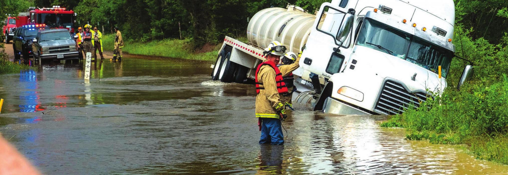 Ledbetter firefighters get ready to rescue local truck driver Tomas Garza after his rig washed off Goehring Road at Cummins Creek Monday afternoon. Photo by Andy Behlen