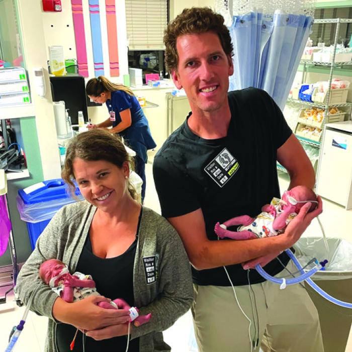 Diane holding Daniel and Kenn holding Owen. This was the first time the babies got to wear clothes, a neonatal intensive care unit milestone. Here the boys are in matching onesies.