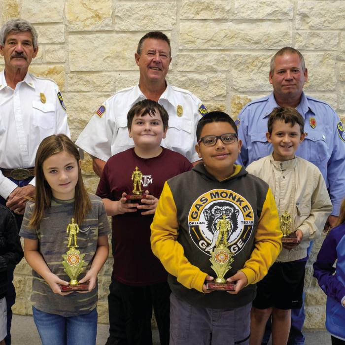 Winners of the fire poster contest for Grades 3-4 at La Grange Elementary went to (front, from left) Kamri Shaw, Byron Lopez and Audrey Pietsch. Honorable mention winners were (middle row) Desi Perez, Rilan Karisch and Jaydon Faldyn. Pictured with them are (back) Asst. Chief Frankie Srubar, Fire Chief Frank Menefee and Capt. Kenneth Chovanec of the La Grange Volunteer Fire Department.