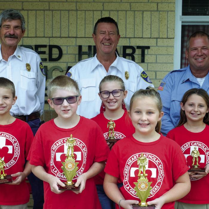 Winners of the fire poster contest for Grades 3-4 at Sacred Heart School went to (front, from left) Sam Janacek and Charli Hadaway. Honorable mention winners were (middle row) Cody Cernosek, Kirtley Kallus and Adalyn Emmel. Pictured with them are (back) Asst. Chief Frankie Srubar, Fire Chief Frank Menefee and Capt. Kenneth Chovanec of the La Grange Volunteer Fire Department. Not pictured was winner Emma Wilkerson.