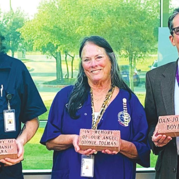Holding one of the new memorial pavers is Mel Burgess, SMMC Facility Director; Mary Kahanek, SMMC Volunteer Coordinator; and Michael Corker, SMMC Foundation President and Board of Directors Vice Chairman.