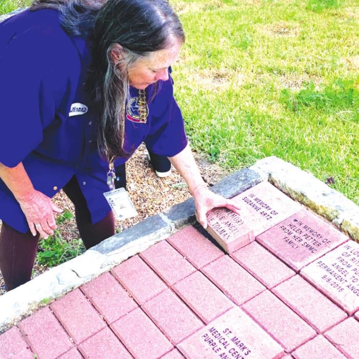 Mary Kahanek, SMMC Volunteer Coordinator, installing one of the new custom pavers.