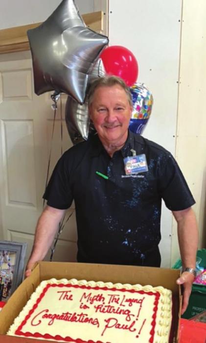Paul Mikula poses with a cake at his retirement celebration Tuesday at HEB. His shirt is covered with remnants of a silly string spraying by his co-workers. Photo by Linda Morrison