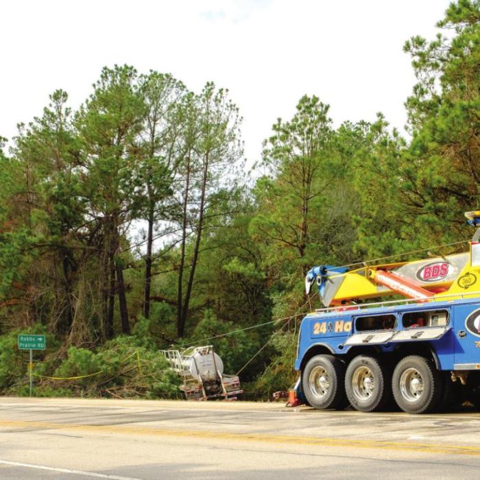 Two heavy duty tow trucks worked together to pull an oilfield tanker out of the pine trees Monday morning. The truck slid off the road after driving across a patch of ice Sunday afternoon. Photo by Andy Behlen
