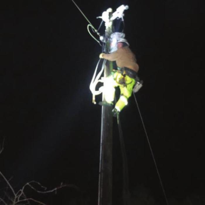 Apprentice Lineman Joey Jasek climbing a pole during the night to pull wire to complete repairs on a downed power line north of Weimar. (Photo credit: Line Foreman Greg Noak)