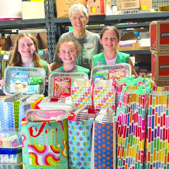 Each Girl Scout troop in Fayette County prepared birthday boxes with all the fixings for a cake and other surprises. On Monday, representatives of Troop 32077 delivered the donations, along with several cases of Girl Scout cookies from their sale stock, to AMEN Food Pantry. Three troop members are shown with Susan Schultz of AMEN.