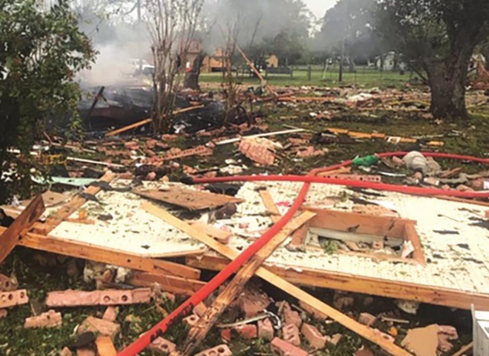 Left: Flames are visible at the site of the home of Michael and Mazie Hess, which exploded Tuesday morning in Ellinger. Right: The remains of the brick home, which was almost totally leveled by the blast. Photos by Joan Herring and Fayette County Sheriff’’s Department