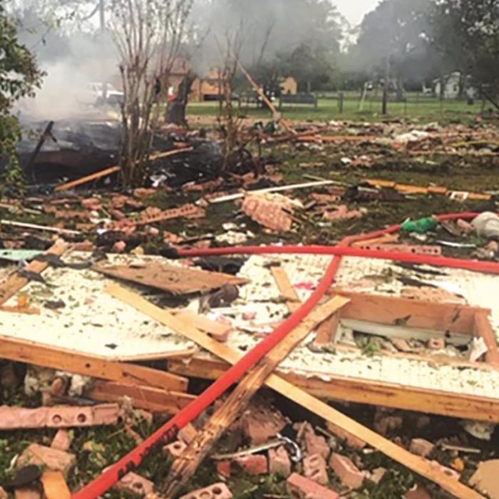 Left: Flames are visible at the site of the home of Michael and Mazie Hess, which exploded Tuesday morning in Ellinger. Right: The remains of the brick home, which was almost totally leveled by the blast. Photos by Joan Herring and Fayette County Sheriff’’s Department