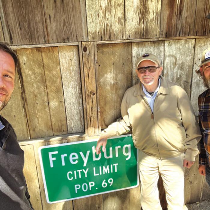Our three cross-county travelers, left to right Jeff Wick, Pancho Howze and Andy Behlen, pose by the Freyburg “city limit’ sign at the Freyburg Hall.
