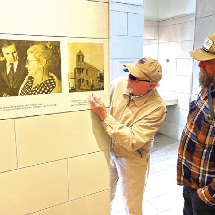 Pancho Howze and Andy Behlen admire the historic photos that are superimposed on tiles in the new bathroom at the Round Top town square.