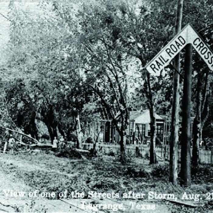 Postcard with caption, “View of one of the Streets after Storm, Aug. 21st, 1909, La Grange, Texas,” shows a family outside a home where the siding had been ripped off. Courtesy of the Fayette Heritage Museum and Archives, La Grange.