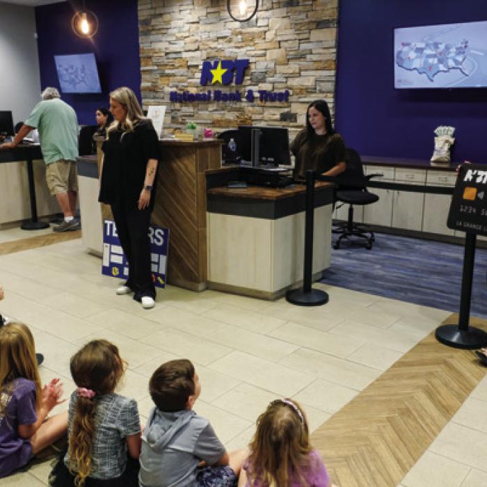 Tellers at the bank teach the students about depositing checks and using debit cards.