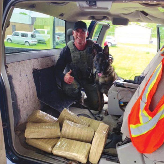 Sgt. Randy Thumann and K9 Kolt with the eight bundles of marijuana found during the traffic stop.