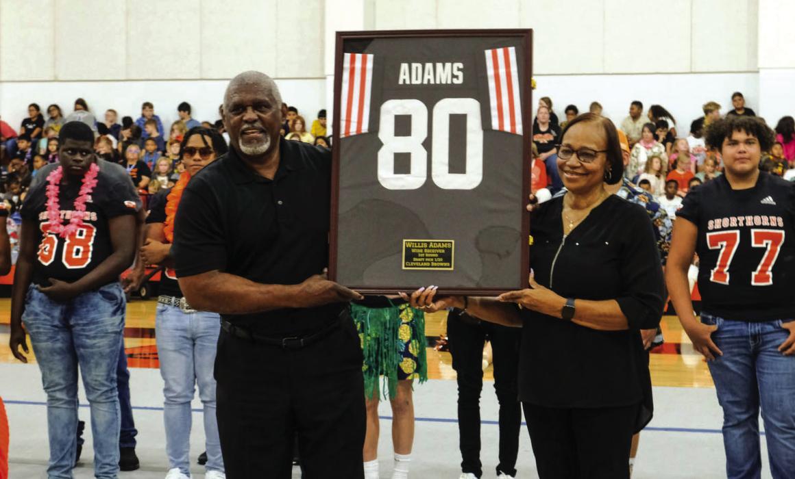 Willis Adams and his wife Natalie hold up a framed jersey that will be on display in the foyer of the Schulenburg High School Gym. The school honored the former Shorthorn during the pep rally on Friday.