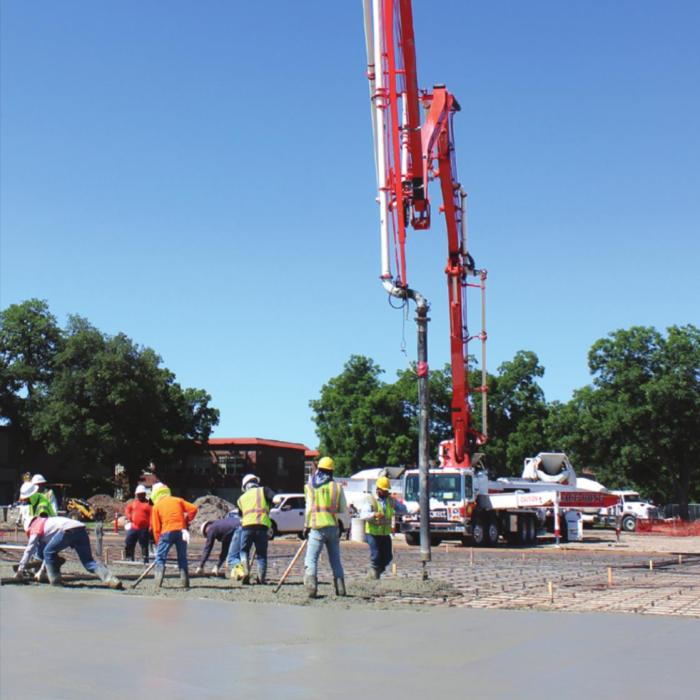 Several people were hard at work Monday smoothing out a steady stream of concrete in the new school parking lot on the corner of Vail and Jackson Streets in La Grange. Photo by Jeff Wick
