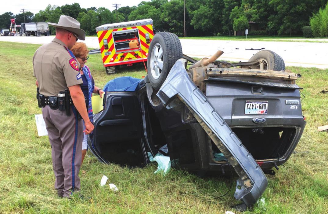 A DPS trooper examines the wreckage of an accident that claimed the lives of a Carmine couple, Ilo and Joyce Ullrich. The 18-wheeler that struck the car can be seen in the background to the left. Photo by H. H. Howze