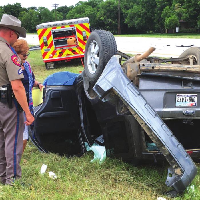 A DPS trooper examines the wreckage of an accident that claimed the lives of a Carmine couple, Ilo and Joyce Ullrich. The 18-wheeler that struck the car can be seen in the background to the left. Photo by H. H. Howze