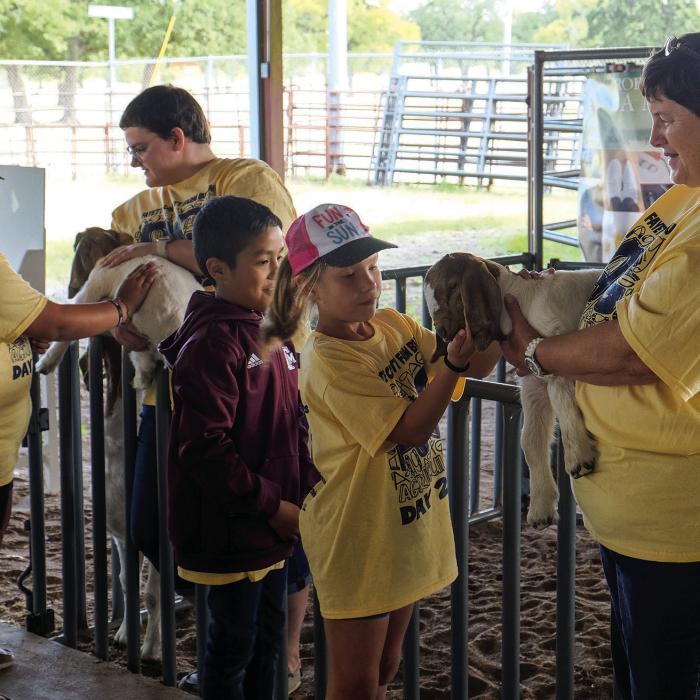 Students got to pet some kid goats after learning about the goat and sheep raising business from Linda Anders (right).