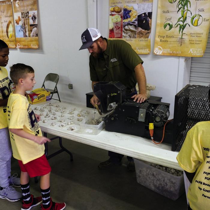 Fayette County AgriLife Extension Agent Scott Wiley shows students how a cotton gin separates cotton lint from seeds and other debris.