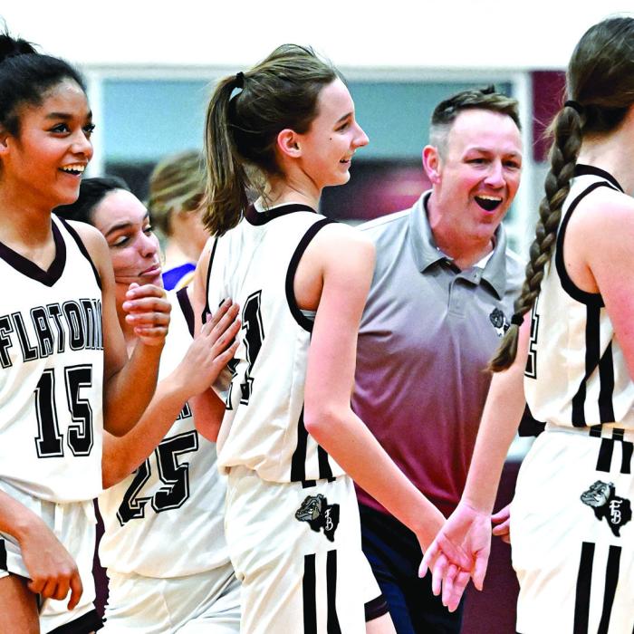 Coach Robert Gray and the Flatonia Lady Bulldogs celebrate with Summer Sodek after she nails a half-court three-point shot in Tuesday’s 47-40 win over the The Weimar Lady Wildcats. The Lady Bulldogs have defeated the Lady Wildcats twice this season. Photo by Stephanie Steinhauser