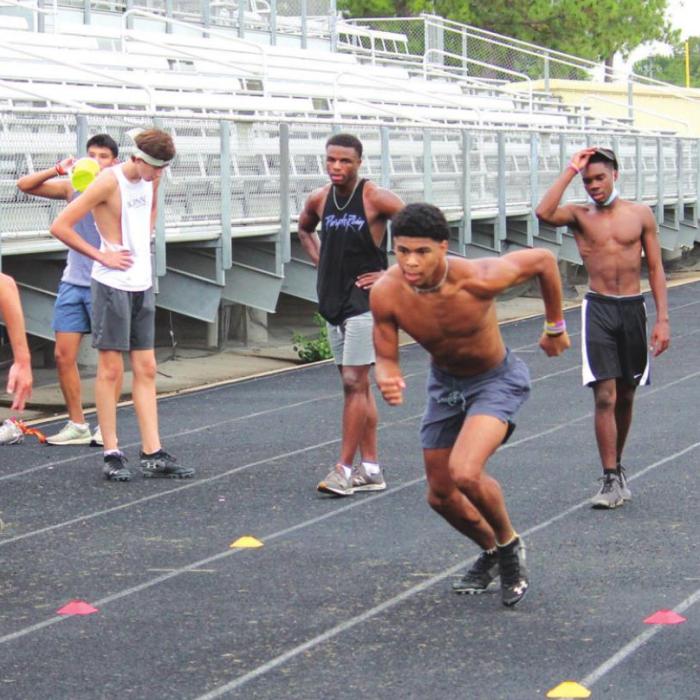 A masked coach James Magness, right, oversees agility drills by La Grange athletes on the track Tuesday morning.