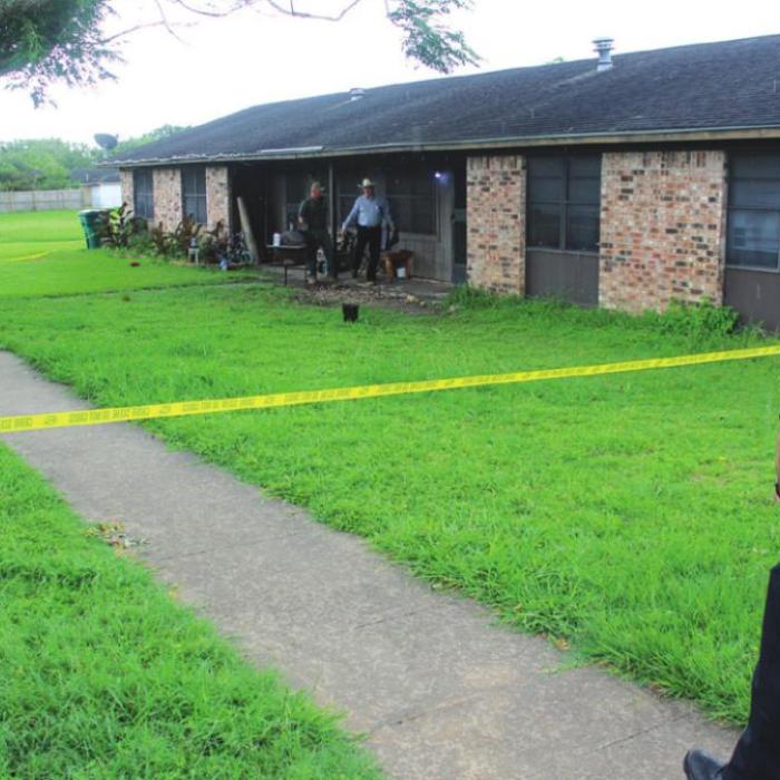 Monday afternoon, La Grange Police Officer Justin Koehne stands outside the crime scene tape surrounding the River Valley Apartment where David Harrison was shot and killed Sunday night. Near the front door, a Texas Ranger and LGPD’s Kenny Schmidt conduct their investigation. Photo by Jeff Wick