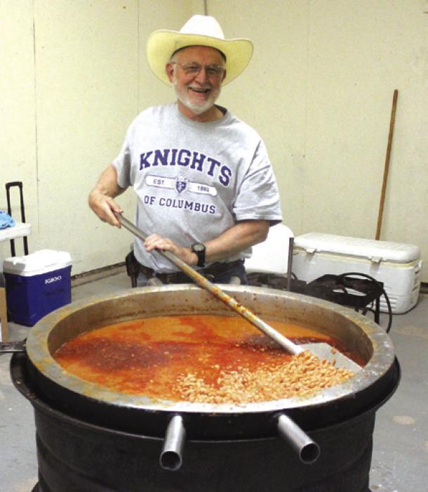 Jim Kothmann stirs up a massive kettle of 120 pounds of beans the Knights of Columbus prepared as part of the cyclists’ supper Saturday at the fairgrounds.