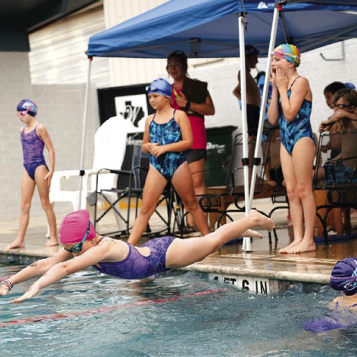 Shelby Janacek dives in on relay as Nora Kerr finished butterfly and Danni Schmidt looks on. Photo by Brittany Dawson