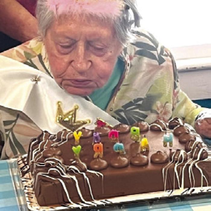 Centenarian Helen Mikus blowing out candles on her cake.