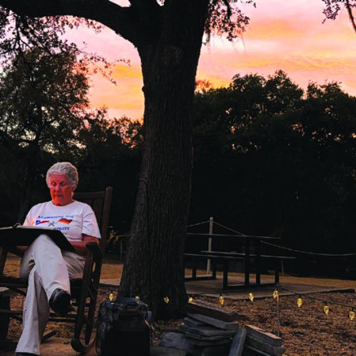 Volunteer Bobbie Nash reads spooky stories as the sun sets as attendees waited for their tours to begin Friday. Photo by Chrystal Wick