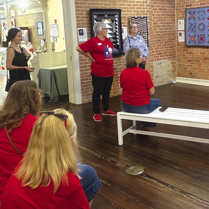 Touring the Texas Quilt Museum (standing left to right) Lisa Slinkard, a museum visitor from California, Terri Wagner, Kim Joost, and Deborah Blanchette Bradley, museum Managing Director. Seated (back bench) Susie Grider; (front bench) Kim Bonewald, Donna Burton.