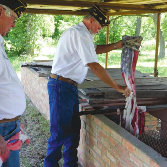 Commander Lyn Reavis and 1st Vice Commander Marvin Wessels of American Legion Post 338 carry out the disposal of the flags during the ceremony.