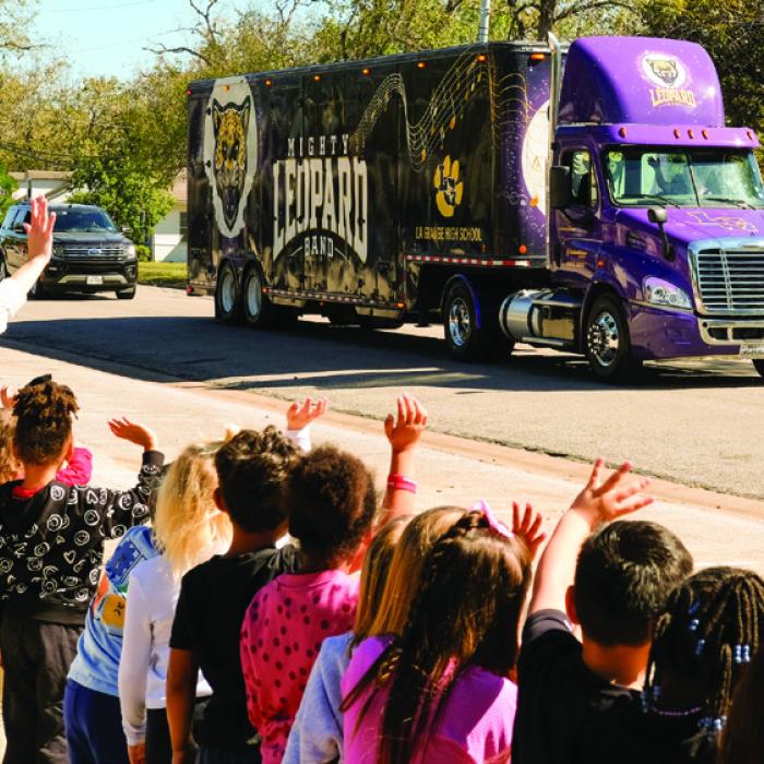 La Grange elementary students line the sidewalks along Milam Street in La Grange to cheer on the Leopard Band members as they headed to San Antonio Tuesday for the state competition. The students rode in style in charter busses. Above is the 18-wheeler hauling the band equipment. Photo by Andy Behlen