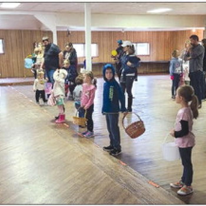 A group of children, with their parents and grandparents, wait patiently to pick up Easter eggs on the Carmine Hall dance floor. The egg hunt was moved to the hall due to the creek and wet grounds at the Carmine City Park.