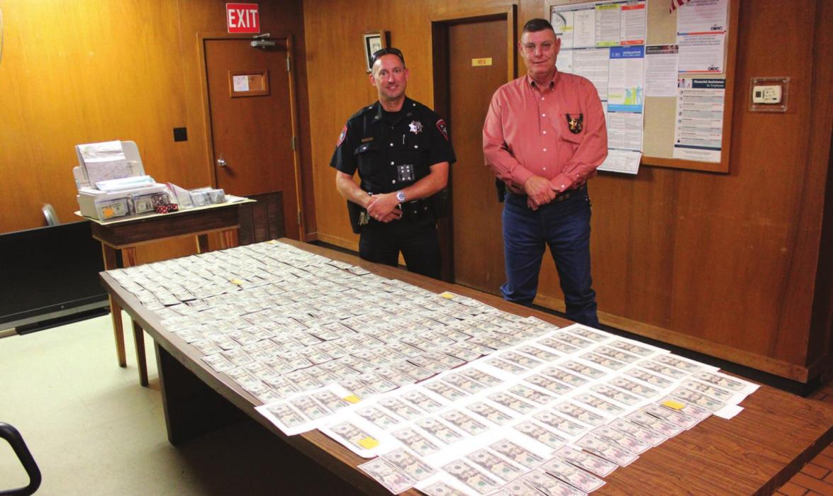La Grange police officer Brian Adams, left, and chief David Gilbreath, right stand behind the counterfeit money Adams found during a recent incident.Photos by Jeff Wick