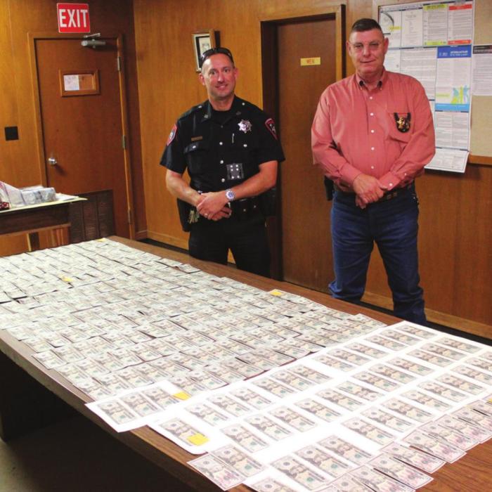 La Grange police officer Brian Adams, left, and chief David Gilbreath, right stand behind the counterfeit money Adams found during a recent incident.Photos by Jeff Wick