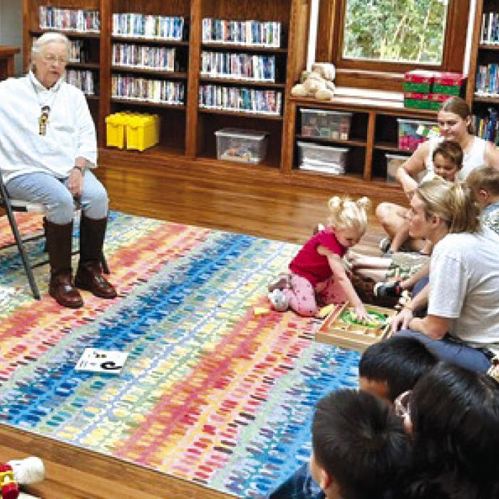 Sally Reynolds reading a book to a group during storytime.
