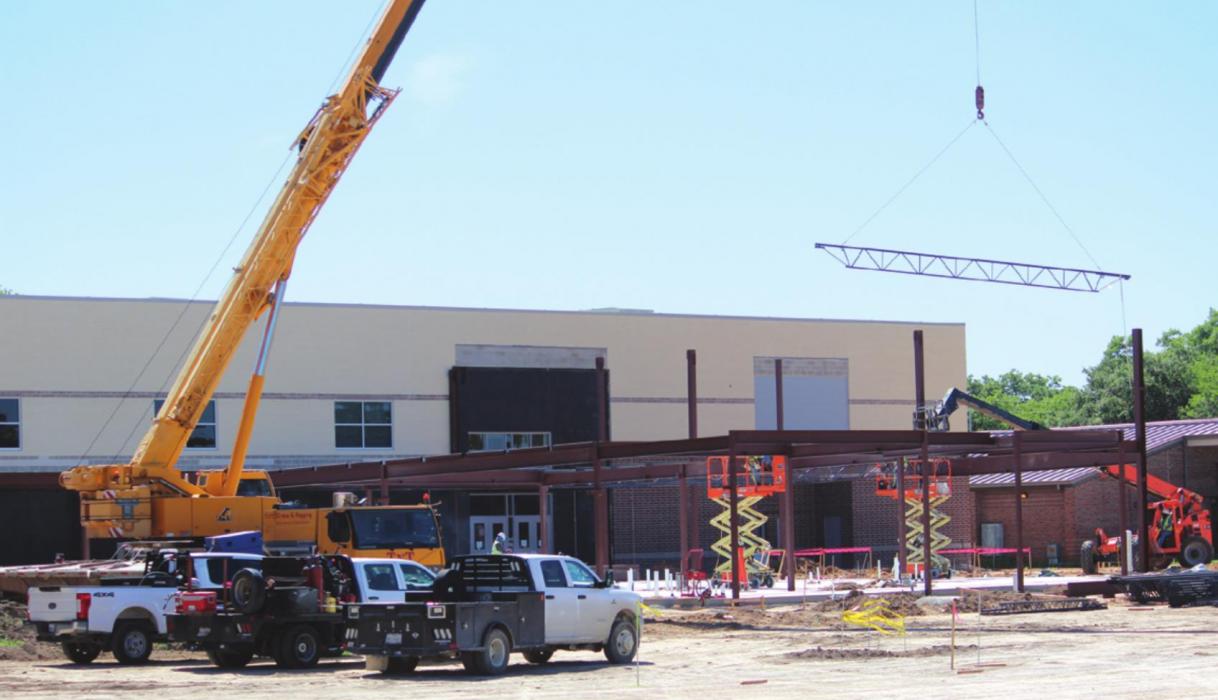 A metal support piece is lowered into place by a crane in what is a very active construction site at what will be the new west-facing entrance to the La Grange elementary complex. Photo by Jeff Wick