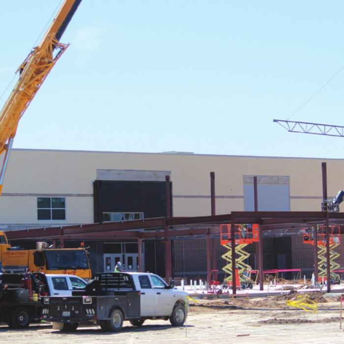 A metal support piece is lowered into place by a crane in what is a very active construction site at what will be the new west-facing entrance to the La Grange elementary complex. Photo by Jeff Wick