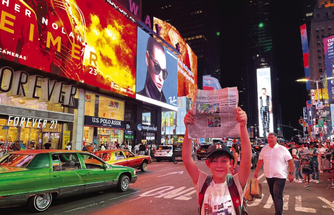 Just like one of the New York newsboys of old, Maddox Wick is shown here hoisting up a copy of The Fayette County Record at Times Square last week. But this copy was not for sale, it traveled with Maddox and his dad, Record editor Jeff Wick, as they took an Amtrak train trip across the country. They visited St. Louis, Chicago, Niagara Falls, New York City and Washington D.C. by train before flying home.